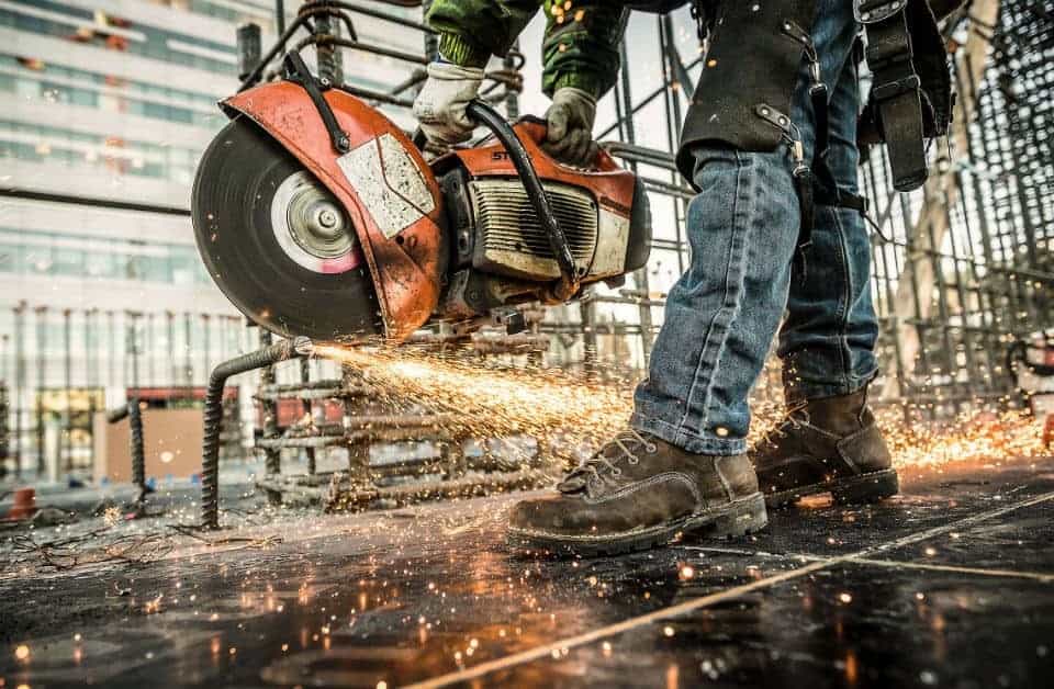 A man wearing construction safety shoes and working on a construction site 